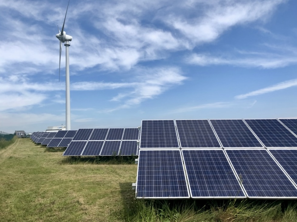 Solar panels in a field with a wind turbine